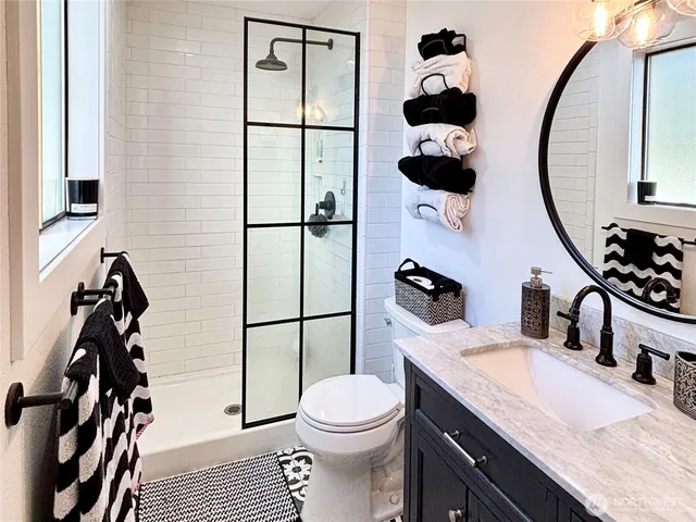 a bathroom with a granite countertop sink mirror vanity and toilet