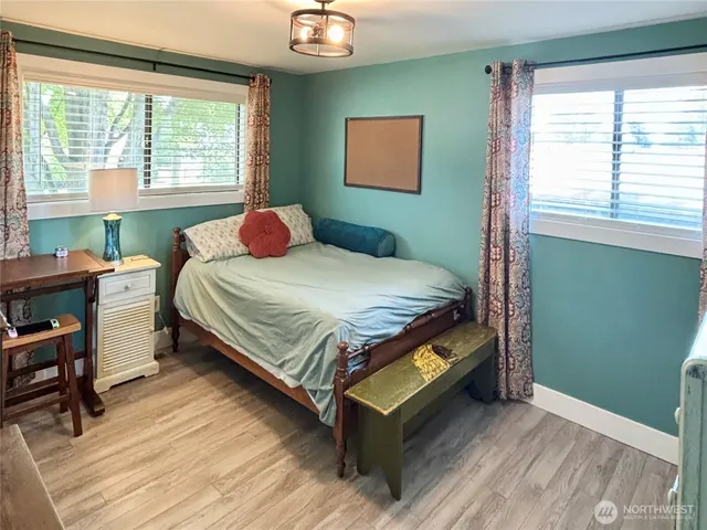 a bedroom with a bed wooden floor and window