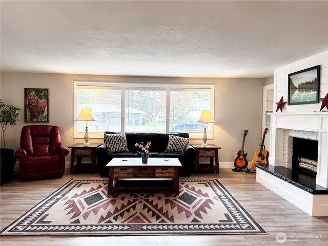 a living room with furniture a fireplace a rug and a large window