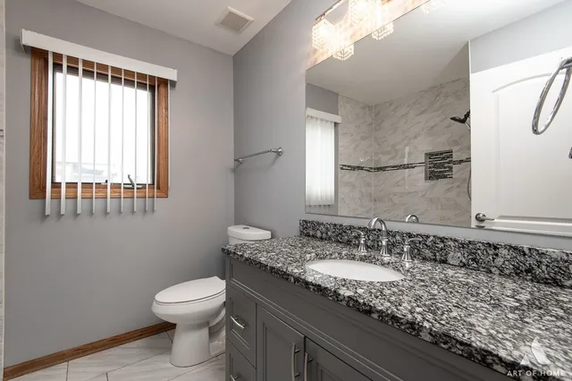 a bathroom with a granite countertop sink a toilet and a mirror