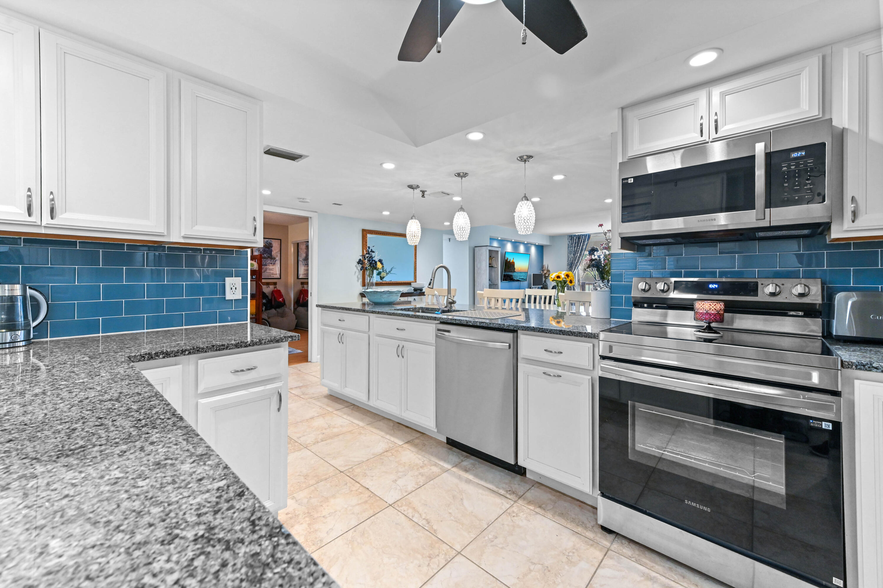 198 Northwest 67th Street, Unit 207 Boca Raton, FL 33487 - Photo 7 of 42 a kitchen with stainless steel appliances granite countertop a stove top oven a sink a microwave and cabinets