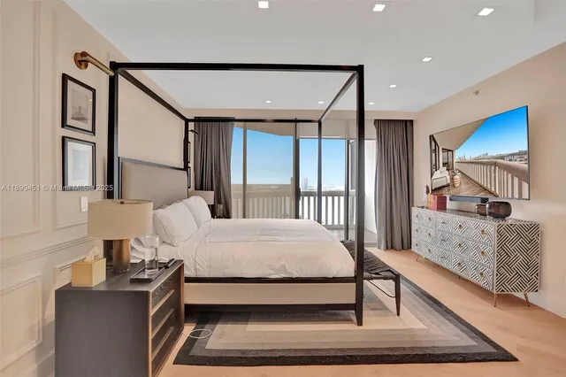 a bedroom with a bed a mirror on dresser and a large window