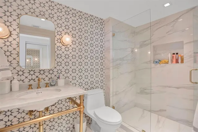 a bathroom with a granite countertop sink a toilet and shower