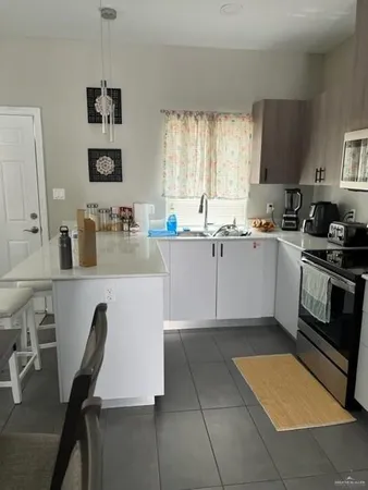 a kitchen with a sink a stove a microwave a counter top space and cabinets