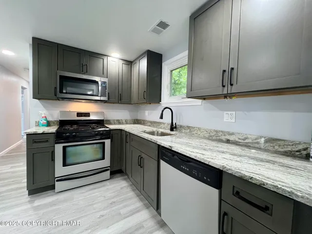 a kitchen with granite countertop a sink and steel appliances