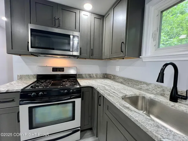 a kitchen with granite countertop stainless steel appliances a stove a microwave a sink and cabinets