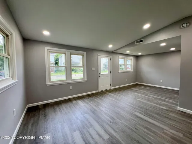an empty room with wooden floor and windows