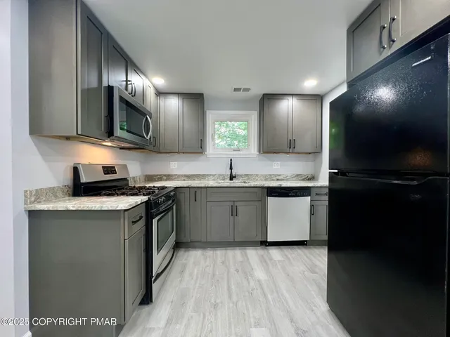 a kitchen with stainless steel appliances granite countertop a sink stove and microwave