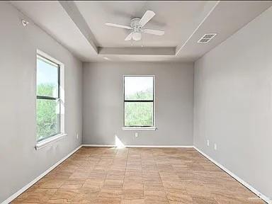 1426 East Rogers Road, Unit 19 Edinburg, TX 78542 - Photo 7 of 13 Spare room featuring plenty of natural light, a raised ceiling, and baseboards