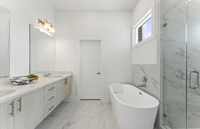 a bathroom with a double vanity sink and mirror with bathtub