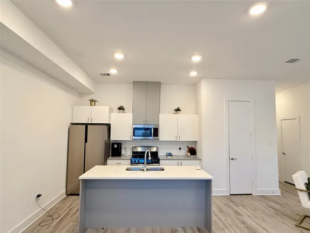 a large kitchen with kitchen island a white counter top space stainless steel appliances and cabinets