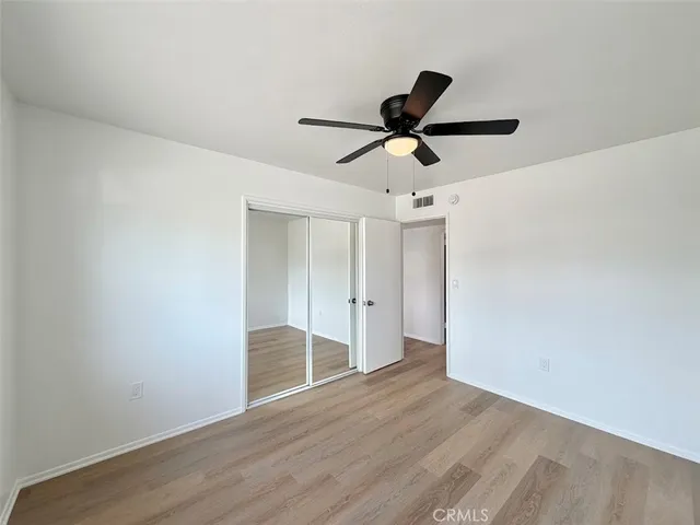 a view of empty room with wooden floor and ceiling fan