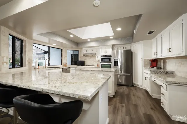 a kitchen with stainless steel appliances granite countertop a sink refrigerator and cabinets