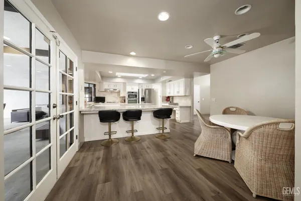 a living room with stainless steel appliances furniture a rug and a kitchen view