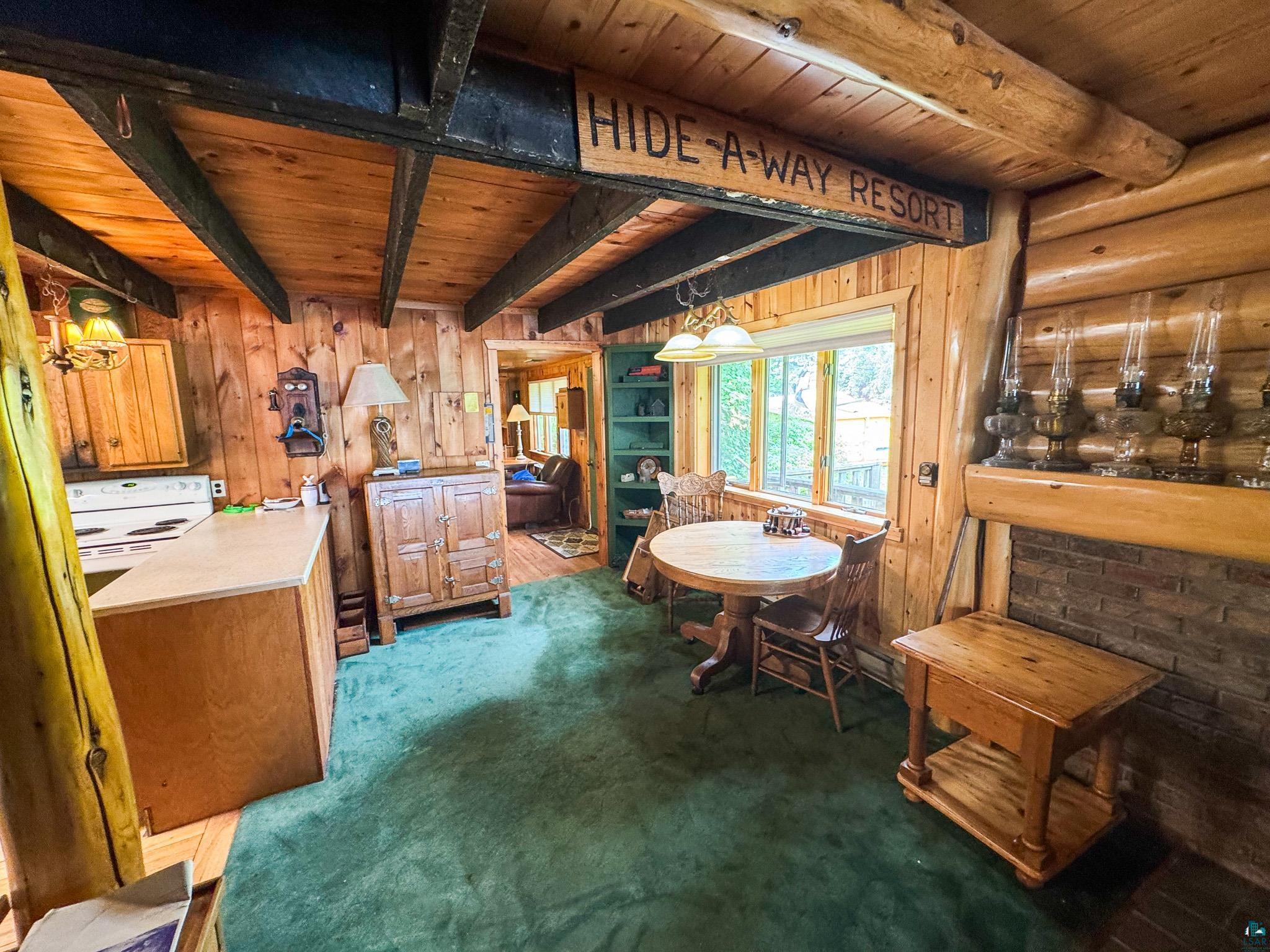 465 South Gunflint Lake Road Grand Marais, MN 55604 - Photo 25 of 46 Wood-paneled interior featuring exposed ceiling beams and a brick-faced fireplace with a log mantle