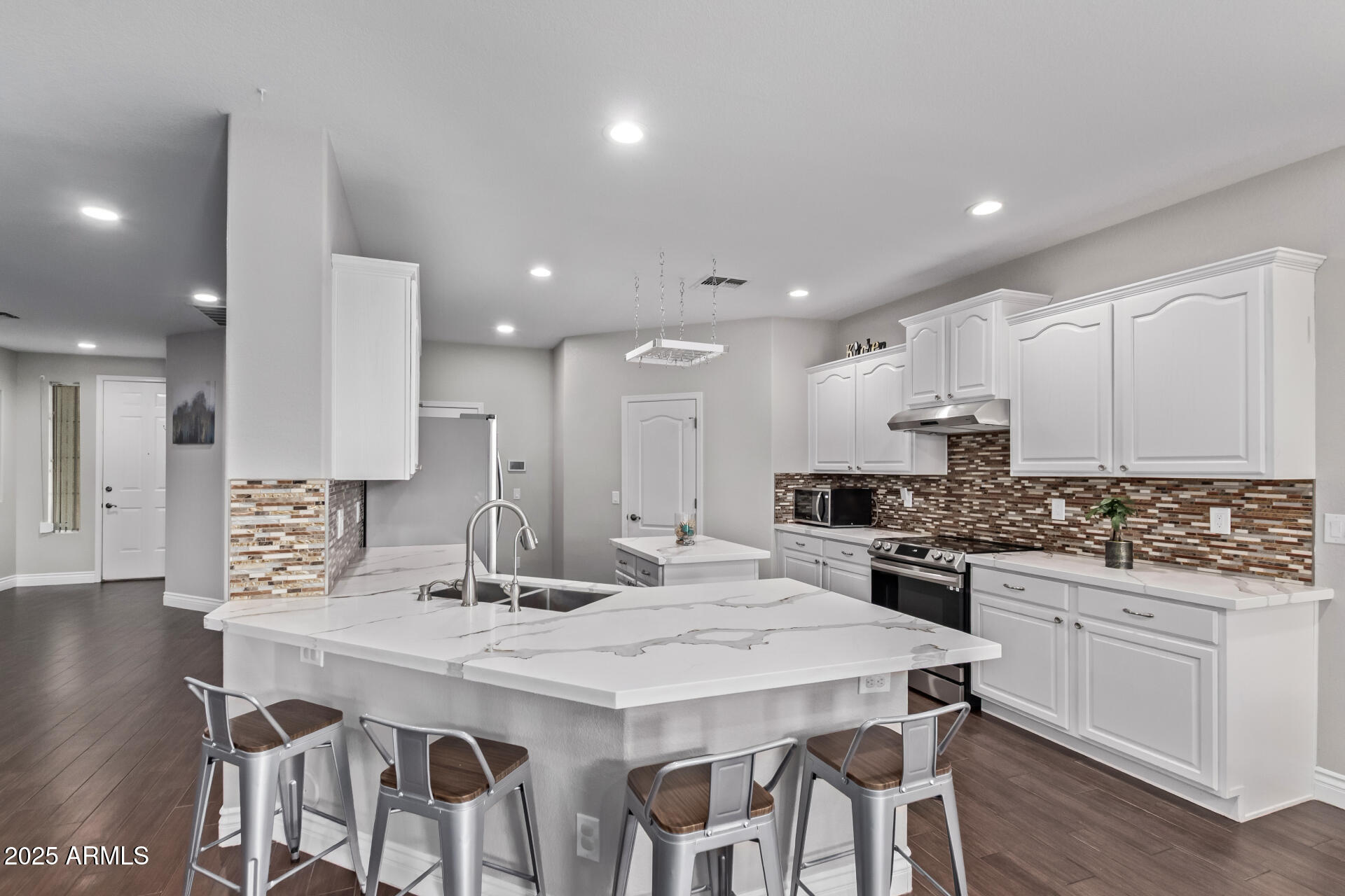 2225 West Carter Road Phoenix, AZ 85041 - Photo 12 of 33 a kitchen with stainless steel appliances kitchen island granite countertop a stove a sink a refrigerator and white cabinets with wooden floor