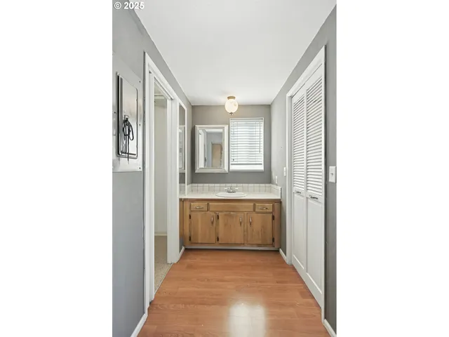 a view of a hallway with wooden floor and a bathroom