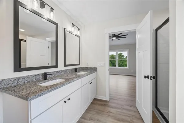 a bathroom with a granite countertop sink a mirror and a shower