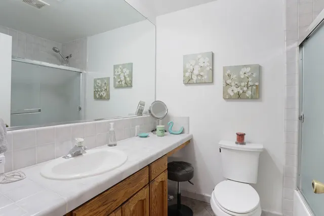 a bathroom with a granite countertop toilet sink and mirror