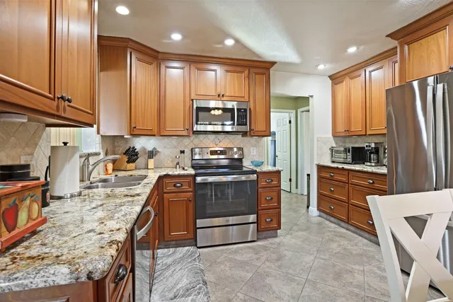 a kitchen with stainless steel appliances granite countertop a stove a sink and a refrigerator
