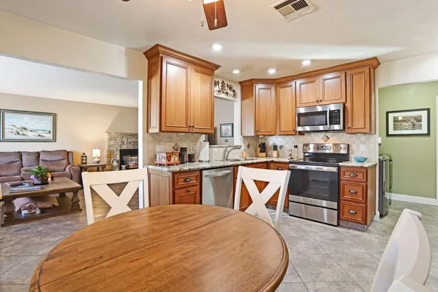 a kitchen with stainless steel appliances granite countertop a stove top oven a sink dishwasher a dining table and chairs with wooden floor