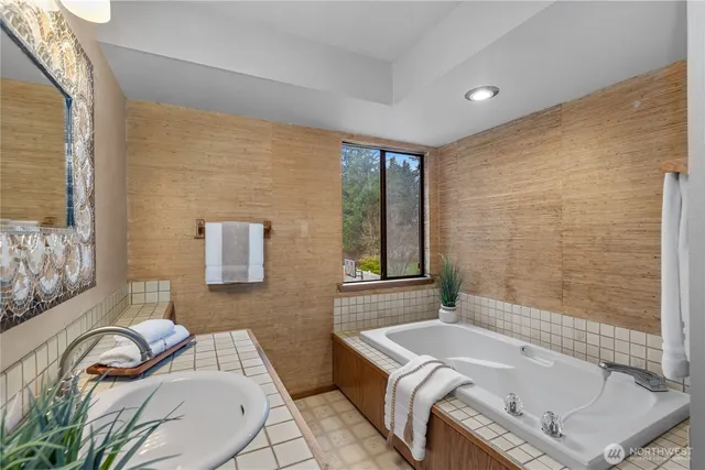 a bathroom with a tub sink and mirror