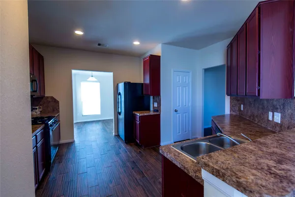 a kitchen with granite countertop a sink stove and refrigerator