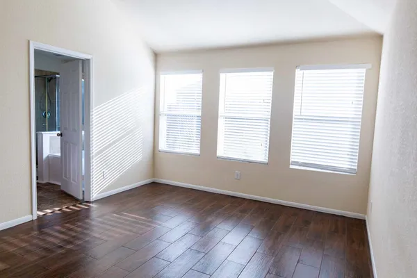 an empty room with wooden floor and windows
