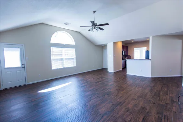 an empty room with wooden floor chandelier and windows