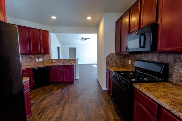 a kitchen with granite countertop wooden cabinets and a stove top oven