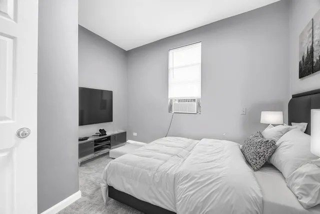 a bedroom with a bed a tv and wooden floor