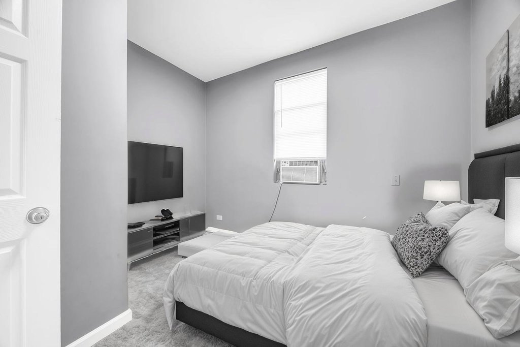 69 East 159th Street Harvey, IL 60426 - Photo 8 of 25 a bedroom with a bed a tv and wooden floor