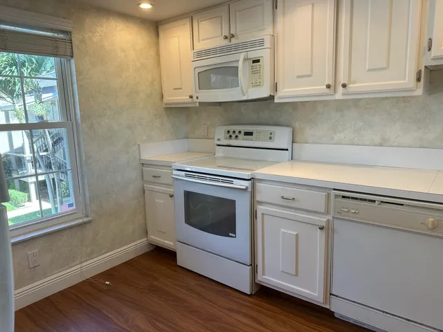 a kitchen with granite countertop white cabinets and white appliances