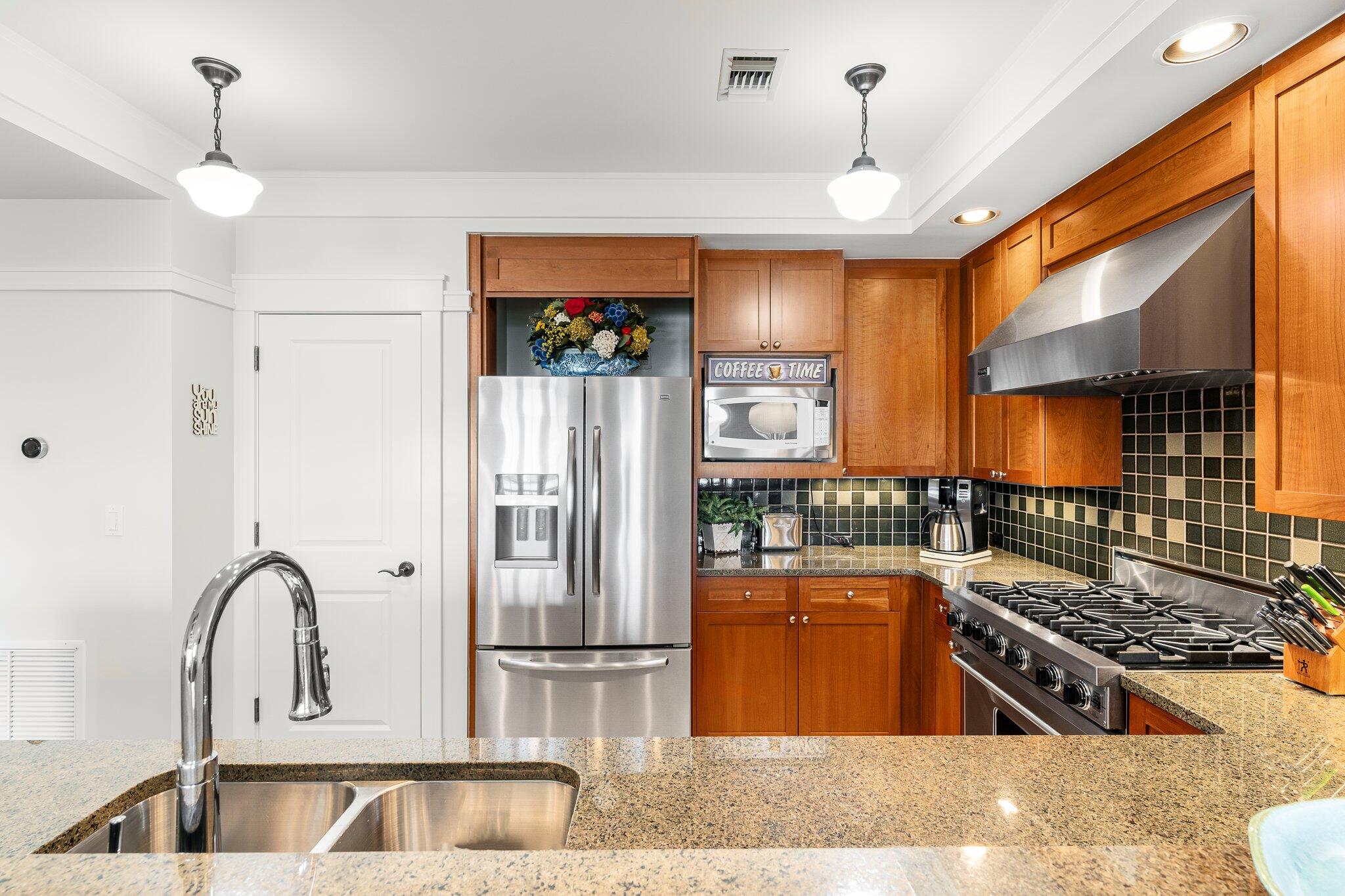 1102 Prospect Promenade, Unit 202 Panama City Beach, FL 32413 - Photo 18 of 35 a kitchen with stainless steel appliances granite countertop a stove a refrigerator and a sink with wooden floor