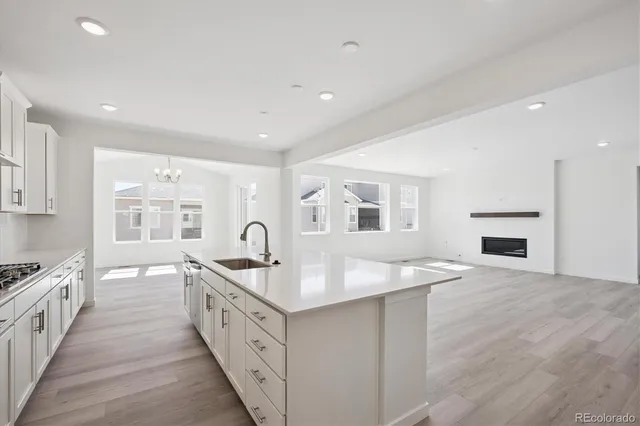 a large white kitchen with granite countertop a sink and dishwasher a stove with wooden floor