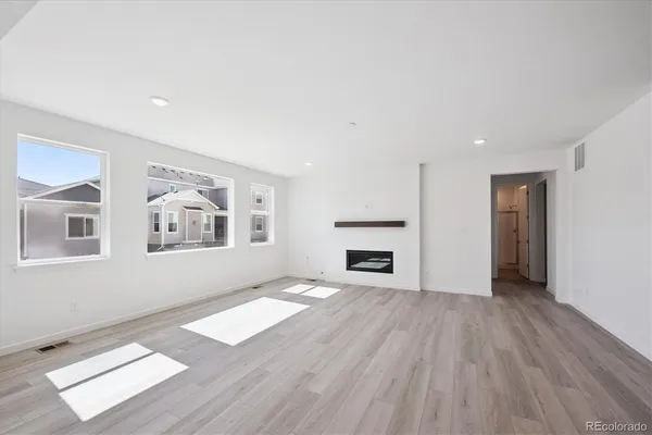 an empty room with windows and fireplace