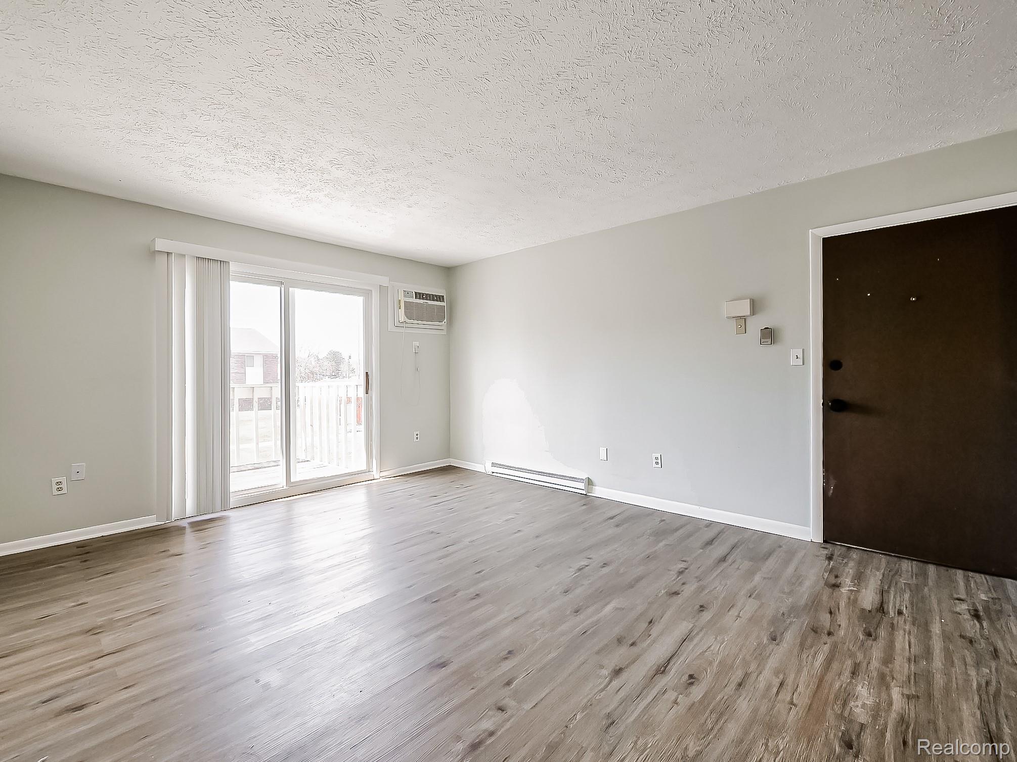 Spare room with light wood finished floors, a textured ceiling, and a baseboard radiator