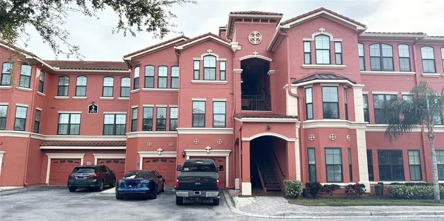 a front view of a building with lot of cars and trees
