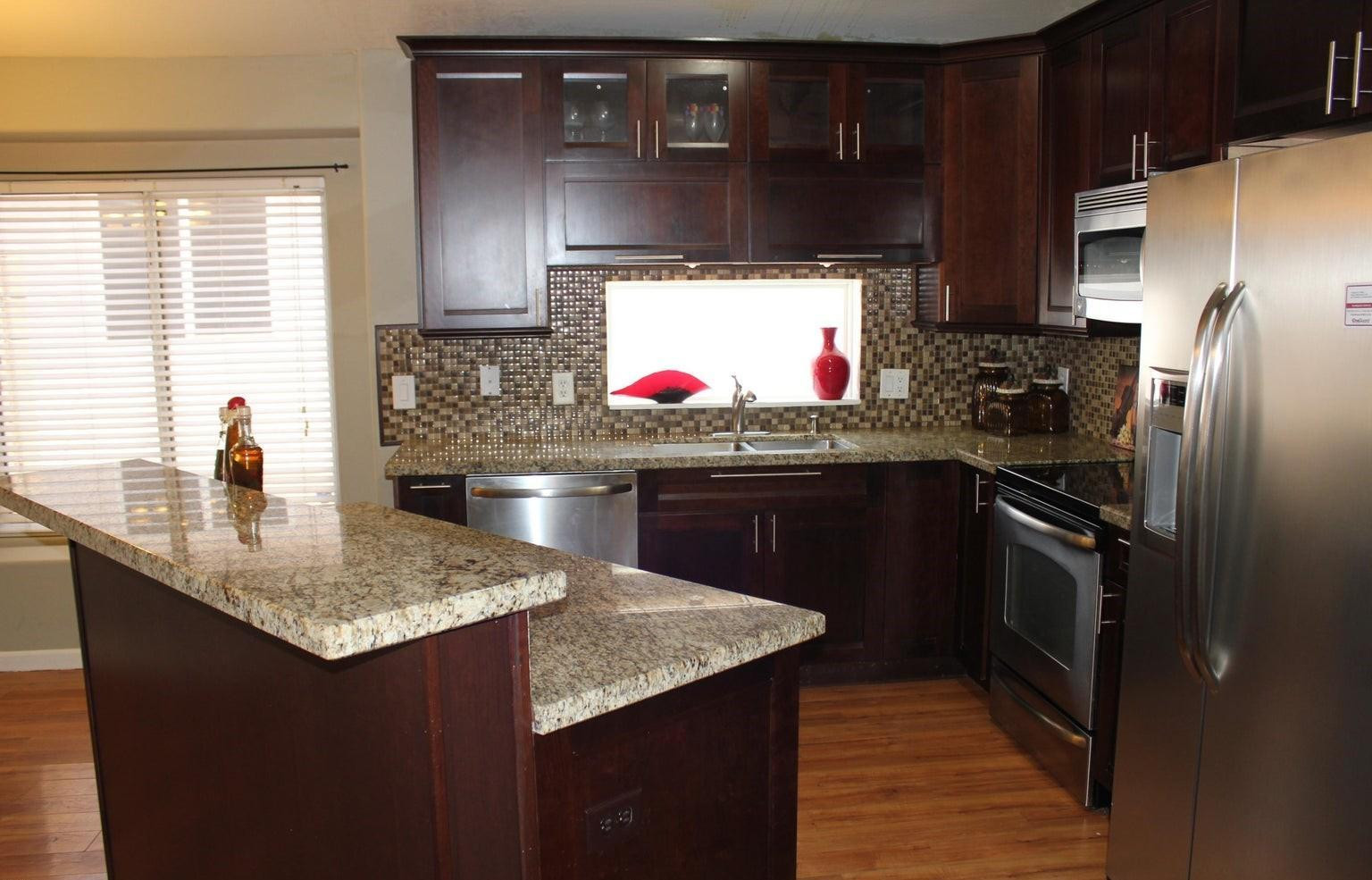 a kitchen with stainless steel appliances granite countertop a sink dishwasher stove and refrigerator