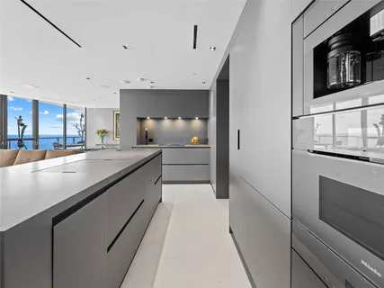 a large white kitchen with granite countertop a large stove top oven and cabinets