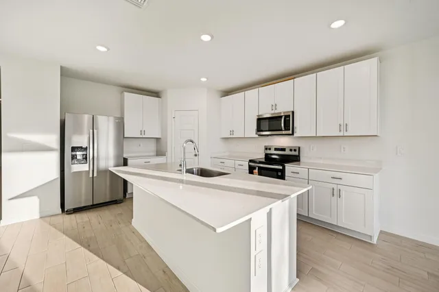a kitchen with a sink a stove a refrigerator a microwave and cabinets