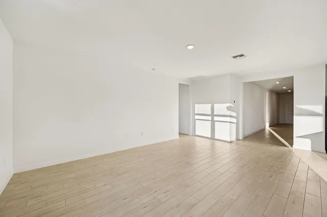 a view of empty room with wooden floor and kitchen
