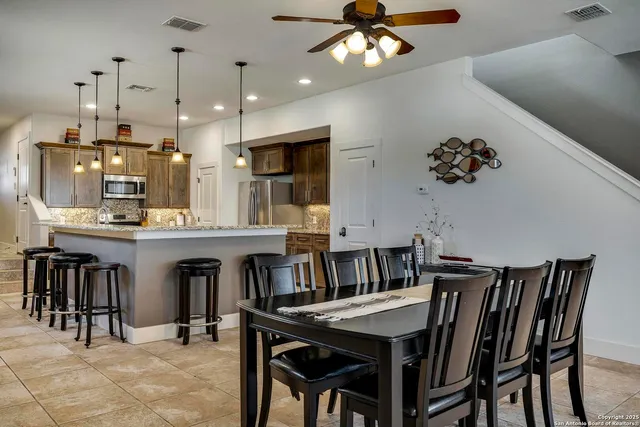 a kitchen with kitchen island a dining table chairs cabinets and stainless steel appliances