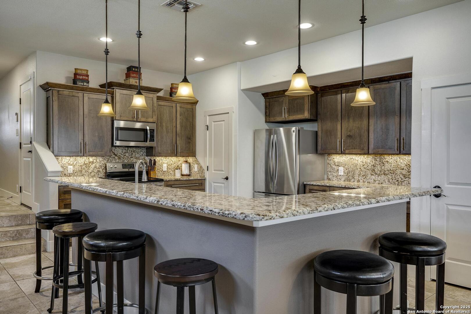 630 3 Oaks Road Seguin, TX 78155 - Photo 6 of 36 a kitchen with stainless steel appliances granite countertop a sink a refrigerator a stove a kitchen island and chairs
