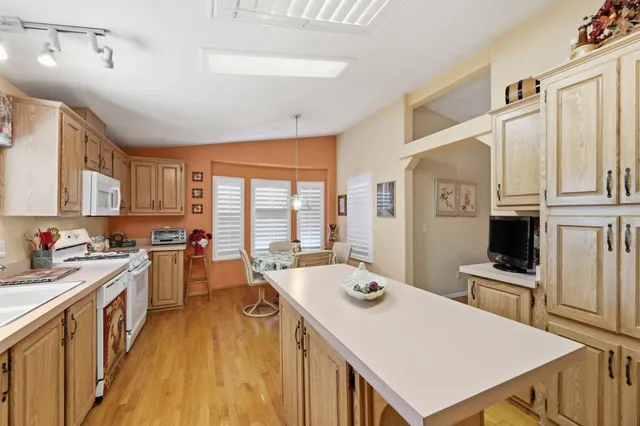a kitchen with a stove a sink dishwasher and a refrigerator with wooden floor
