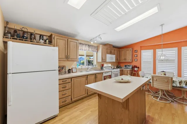 a kitchen with a refrigerator a stove a sink a dining table and chairs