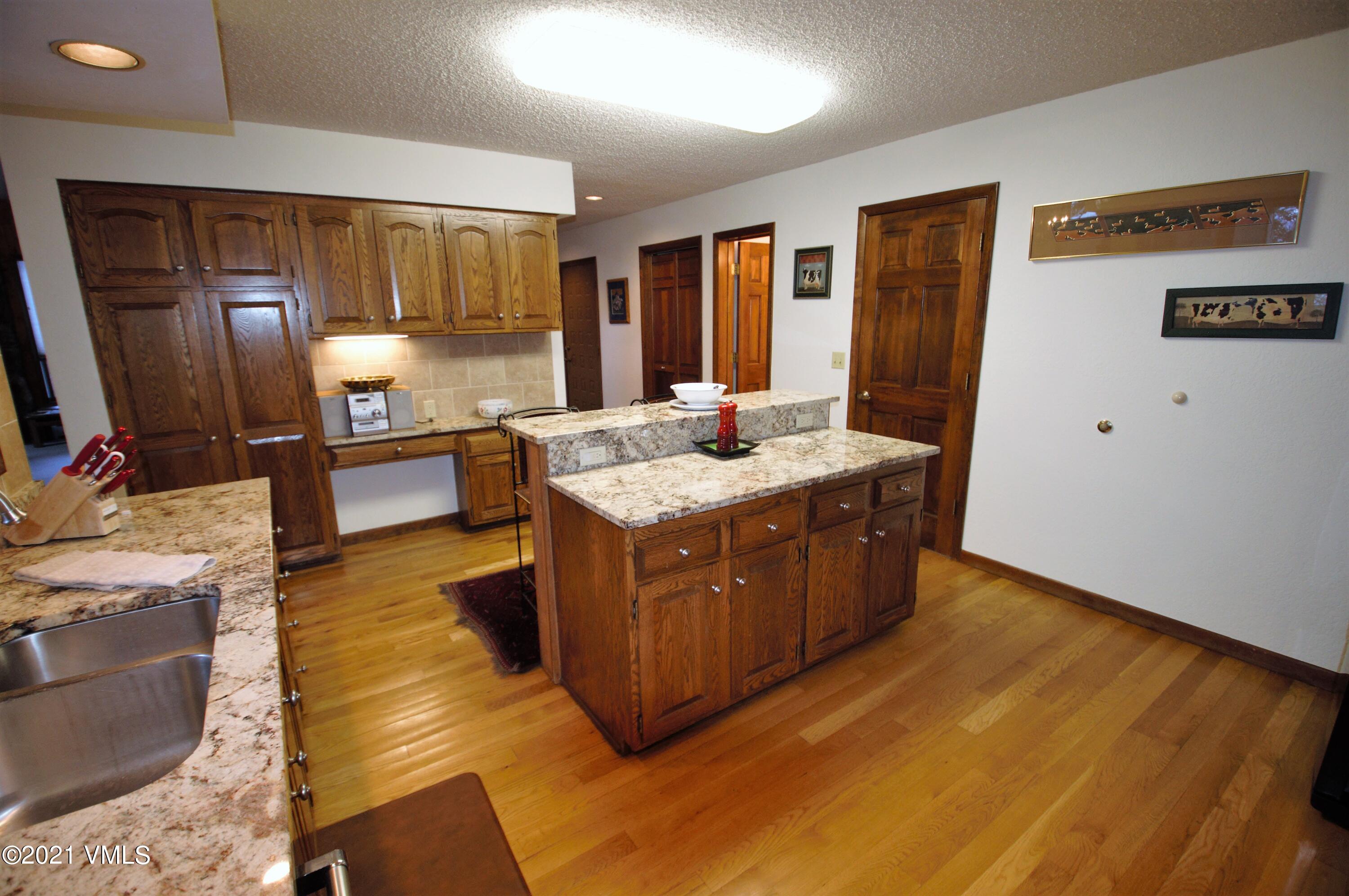 4484 Streamside Circle Vail, CO 81657 - Photo 8 of 29 a kitchen with a stove a sink a refrigerator wooden floor and cabinets
