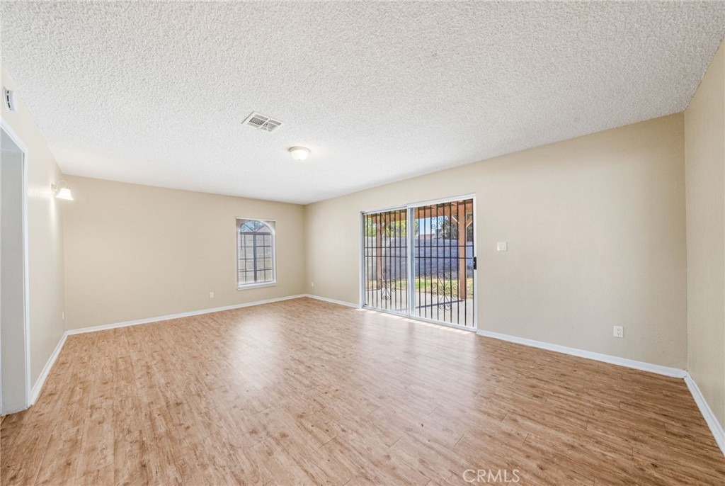 37310 Populus Avenue Palmdale, CA 93552 - Photo 7 of 28 an empty room with wooden floor and windows
