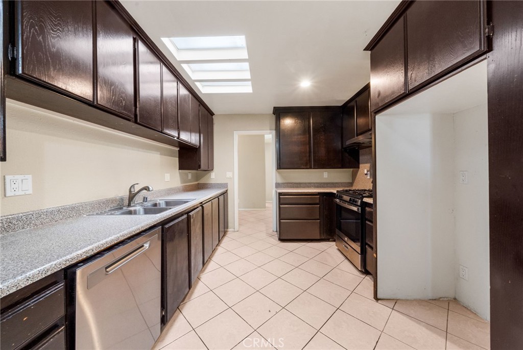 37310 Populus Avenue Palmdale, CA 93552 - Photo 10 of 28 a kitchen with stainless steel appliances kitchen island granite countertop a refrigerator a sink and wooden cabinets