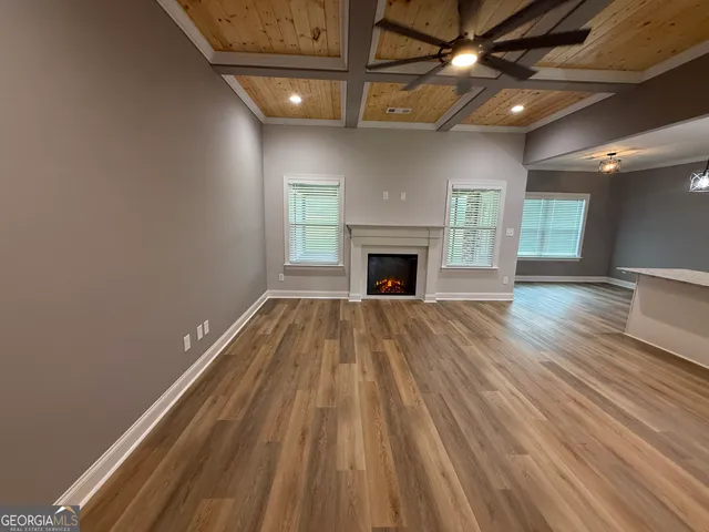 a view of an empty room with window and wooden floor